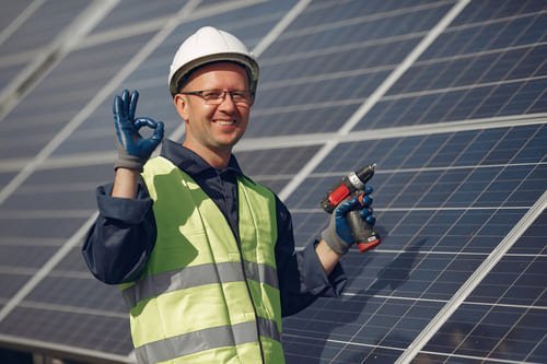 engenheiro sorrindo perto de painel de energia solar